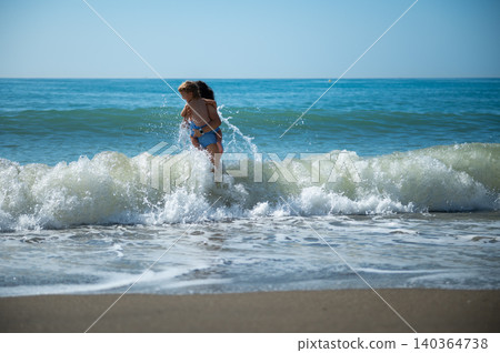 Mother Carrying Child Through Splashing Ocean Wave Mother Carrying Child Through Splashing Ocean Wave 140364738