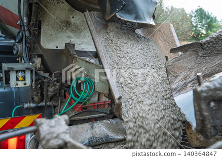 Mixer truck pouring concrete on a roadworks construction site in England for paving and repairs Mixer truck pouring concrete on a roadworks construction site in England for paving and repairs 140364847