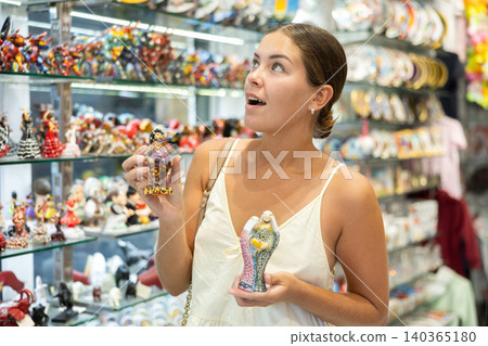 Female traveler buyer chooses ceramic statuette 140365180