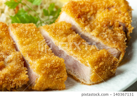 Pork loin cutlet with visible cross-section, served on a white plate with cabbage. 140367131