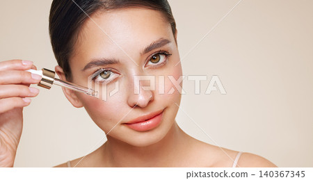 Young beautiful woman applying face serum Young beautiful woman applying face serum 140367345