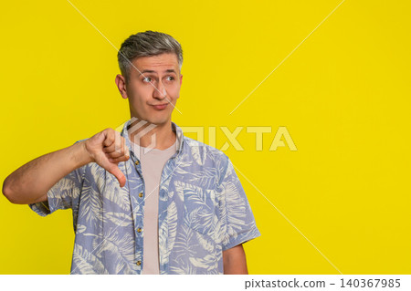 Man showing thumbs down with serious expression disapproving something with negative strong reaction Man showing thumbs down with serious expression disapproving something with negative strong reaction 140367985