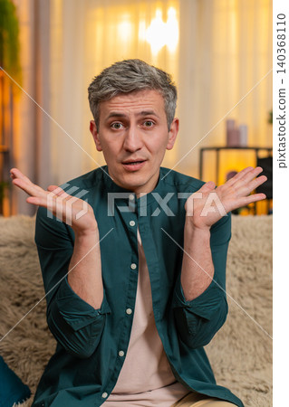 Young man lifts hands in air and looks confused reacting to unexpected situation or sudden question Young man lifts hands in air and looks confused reacting to unexpected situation or sudden question 140368110
