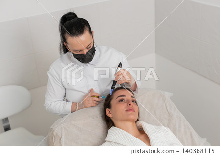 Woman receives microneedling and injections for hair growth scalp therapy in trichology clinic Woman receives microneedling and injections for hair growth scalp therapy in trichology clinic 140368115