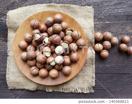 Macadamia nuts on a wooden plate with burlap Macadamia nuts on a wooden plate with burlap 140368621