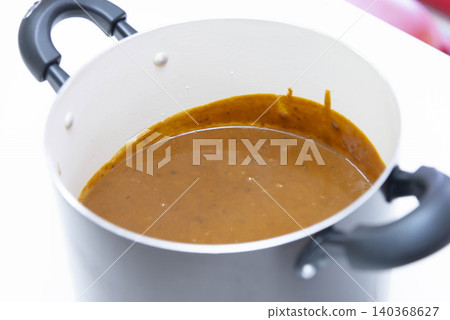 A photo of a rich Japanese curry roux being cooked in a white, double-handled pot. A photo of a rich Japanese curry roux being cooked in a white, double-handled pot. 140368627