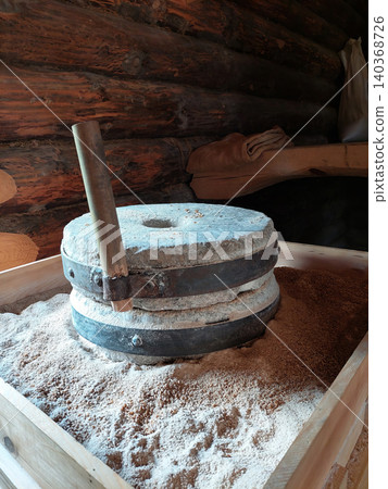 Close-up of authentic millstones with ground flour and wheat grain, traditional craft and heritage. Close-up of authentic millstones with ground flour and wheat grain, traditional craft and heritage. 140368726