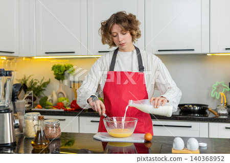 Young woman redhead happy whisking eggs with milk in kitchen for healthy diet breakfast prep at home Young woman redhead happy whisking eggs with milk in kitchen for healthy diet breakfast prep at home 140368952