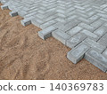 Paving the road from garden bricks by a professional paver. Laying gray concrete paving slabs on a gravel and sand base. 140369783