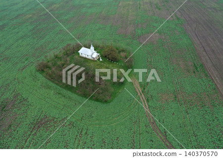 Aerial view of small white chapel in the middle of agricultural field Aerial view of small white chapel in the middle of agricultural field 140370570
