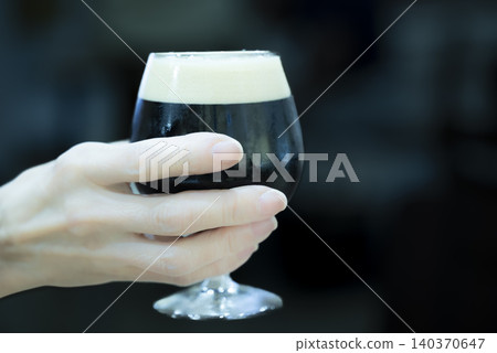 Woman holding a dark beer 140370647