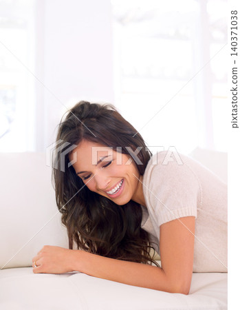 Portrait, laughing or happy woman on couch to relax in living room on holiday in a house or apartment. Lying down, sofa or funny person with smile or wellness on vacation break to rest in alone time 140371038
