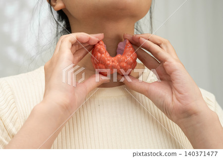 Hyperthyroidism, Overactive Thyroid, Thyroid Lymphoma, Asian woman with thyroid gland human anatomy model. Hyperthyroidism, Overactive Thyroid, Thyroid Lymphoma, Asian woman with thyroid gland human anatomy model. 140371477