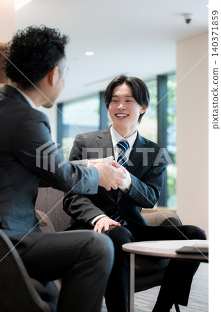 A video showcasing a successful business deal, collaboration, and agreement, featuring a young salesman shaking hands with the president of a beautiful company – an image of the relationship between management and salesperson. A video showcasing a successful business deal, collaboration, and agreement, featuring a young salesman shaking hands with the president of a beautiful company – an image of the relationship between management and salesperson. 140371859