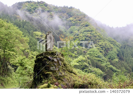 A stone monument and fresh greenery in a mountain village shrouded in mist. A stone monument and fresh greenery in a mountain village shrouded in mist. 140372079