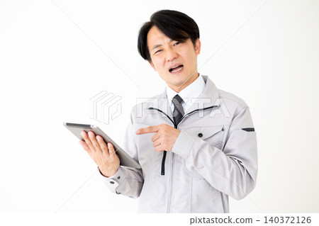 一位身穿灰色工作服的中年商人,在白色背景下看著平板電腦,神情沮喪。 一位身穿灰色工作服的中年商人,在白色背景下看著平板電腦,神情沮喪。 140372126