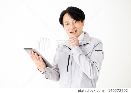 一位身穿灰色工作服的中年商人,在白色背景下看著平板電腦,臉上露出驚訝的表情。 一位身穿灰色工作服的中年商人,在白色背景下看著平板電腦,臉上露出驚訝的表情。 140372392