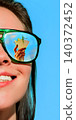 Half face woman in green sunglasses with martini cocktail reflected in lens on blue sky 140372452