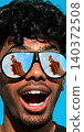 Excited man in sunglasses with beer bottle reflected in lenses on blue summer background. 140372508