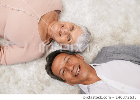 Portrait, elderly or happy couple on carpet to relax in home for bonding or support together. Smile, old people or man lying down on mat by a senior woman for love, retirement or care in marriage 140372633