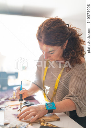 Female artisan creating intricate designs with soldering iron Female artisan creating intricate designs with soldering iron 140373008