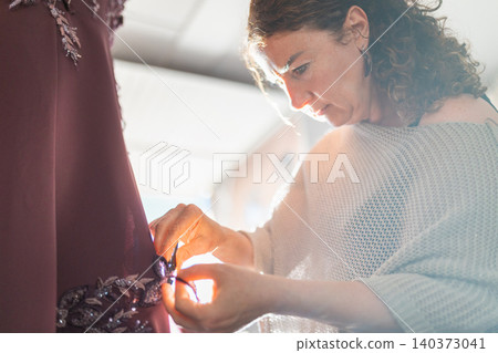 Craftswoman hands creating elegant gown fashion embroidery details Craftswoman hands creating elegant gown fashion embroidery details 140373041