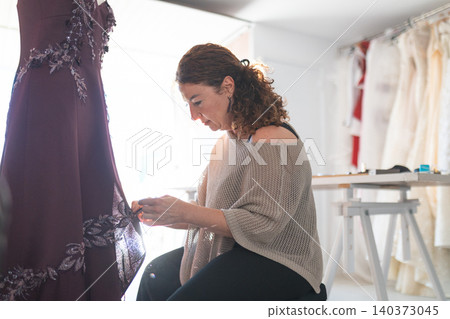 Tailor craftswoman working on custom embroidered dress 140373045