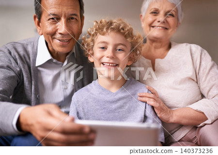 Happy family, portrait and grandparents with child on tablet for entertainment, social media or research on sofa at home. Grandma, grandpa and kid smile with technology for online connection at house Happy family, portrait and grandparents with child on tablet for entertainment, social media or research on sofa at home. Grandma, grandpa and kid smile with technology for online connection at house 140373236