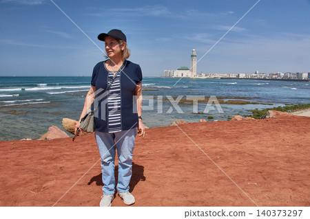 Mature woman admiring the spectacular Hassan II Mosque from the Casablanca coast in Morocco Mature woman admiring the spectacular Hassan II Mosque from the Casablanca coast in Morocco 140373297