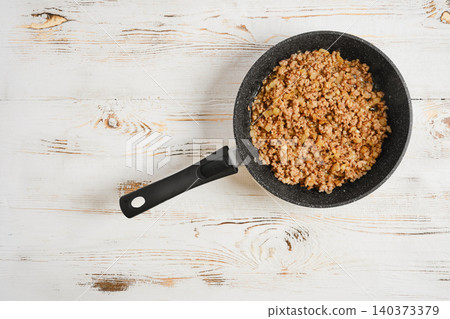 Ground meat cooking in a skillet on white wooden surface at home kitchen Ground meat cooking in a skillet on white wooden surface at home kitchen 140373379