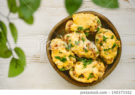 Delicious stuffed potatoes with cheese served on wooden plate during afternoon gathering Delicious stuffed potatoes with cheese served on wooden plate during afternoon gathering 140373382