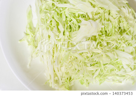 The texture of finely shredded cabbage piled high on a white plate. 140373453