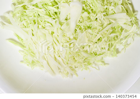 The texture of finely shredded cabbage piled high on a white plate. The texture of finely shredded cabbage piled high on a white plate. 140373454