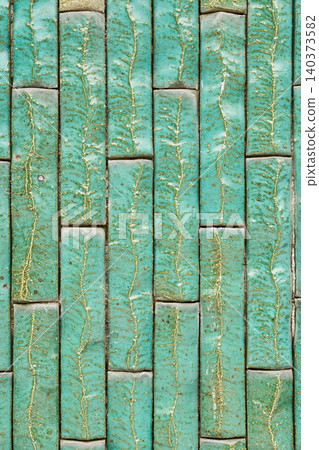 A vertical wall texture featuring long, narrow vintage emerald green tiles with beautiful crazing and color variations. A vertical wall texture featuring long, narrow vintage emerald green tiles with beautiful crazing and color variations. 140373582