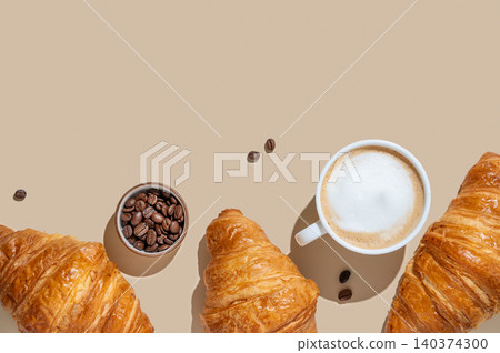 Cup of cappuccino, coffee beans and croissants on a yellow isolated background 140374300