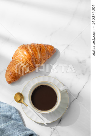 Freshly brewed black coffee in a cup on a white marble background with croissant Freshly brewed black coffee in a cup on a white marble background with croissant 140374304