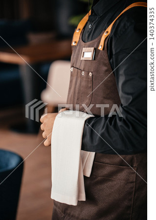 Professional waiter in apron holding service towel in restaurant ready for guests 140374335