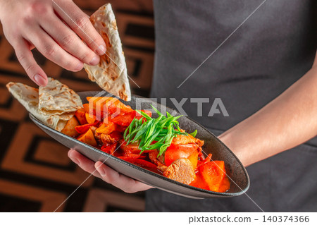 Chef Holding Spicy Meat Stir Fry with Vegetables and Flatbread Chef Holding Spicy Meat Stir Fry with Vegetables and Flatbread 140374366