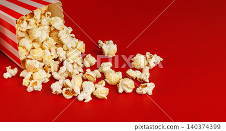 Movie popcorn spilling on red background. Concept of home cinema, streaming and fun. Movie popcorn spilling on red background. Concept of home cinema, streaming and fun. 140374399