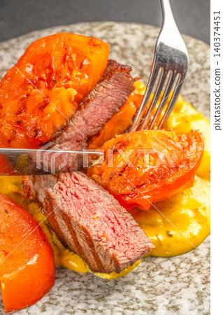 Sliced beef steak with grilled tomatoes and creamy sauce close up gourmet cuisine 140374451