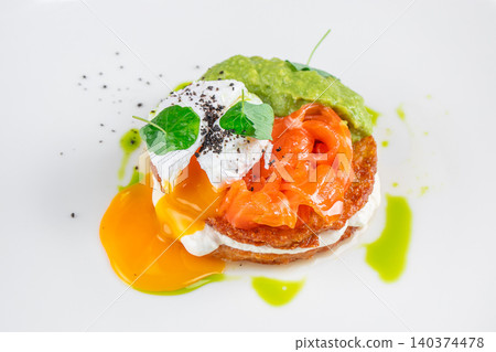 Smoked salmon toast with poached egg avocado and runny yolk on white plate close up Smoked salmon toast with poached egg avocado and runny yolk on white plate close up 140374478
