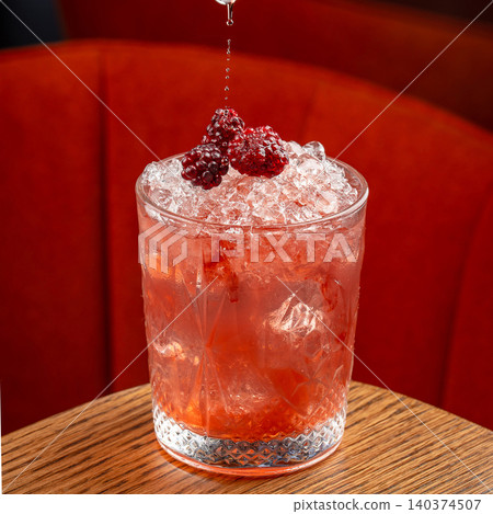Pink cocktail with blackberries ice and falling splash in crystal glass on red background Pink cocktail with blackberries ice and falling splash in crystal glass on red background 140374507