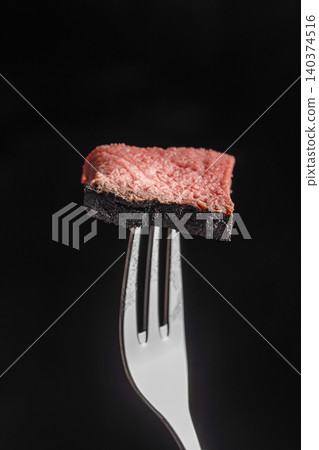 Medium rare grilled beef steak slice on fork isolated on black background with copy space Medium rare grilled beef steak slice on fork isolated on black background with copy space 140374516