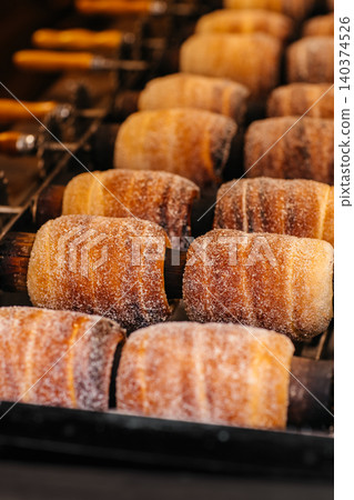 Traditional Czech chimney cakes coated with sugar baking on rotisserie grill 140374526