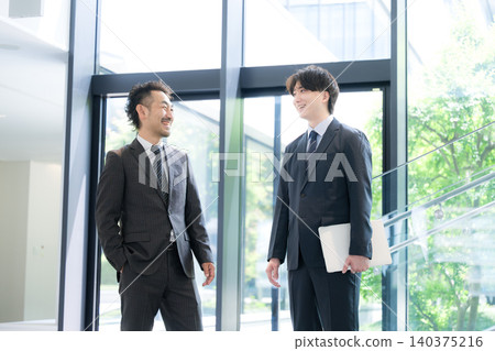 一位年輕的商人、他的老闆和一位客戶在綠意盎然的辦公室裡,隔著窗戶交談──這象徵著他們的溝通交流。 一位年輕的商人、他的老闆和一位客戶在綠意盎然的辦公室裡,隔著窗戶交談──這象徵著他們的溝通交流。 140375216