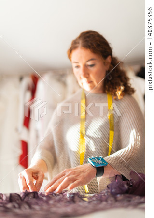 Craftswoman fashion designer working on garment in workshop Craftswoman fashion designer working on garment in workshop 140375356