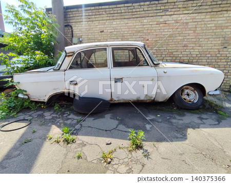 Abandoned White Retro Car Parked near Antique Brick Wall Abandoned White Retro Car Parked near Antique Brick Wall 140375366