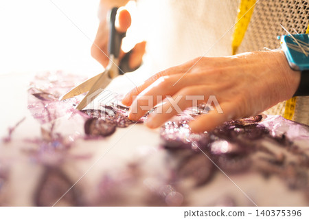 Craftswoman cutting intricate fabric with scissors for fashion design Craftswoman cutting intricate fabric with scissors for fashion design 140375396