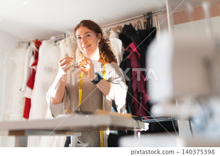 Female tailor creating fabric item in design studio 140375398