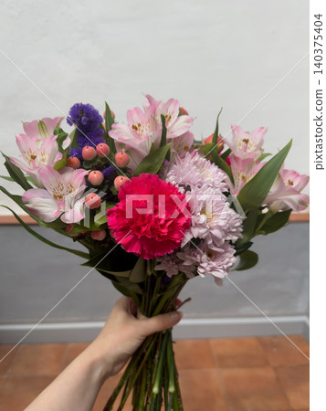 Pink Flower Bouquet with Carnation and Alstroemeria Held in Female Hand Vertical Pink Flower Bouquet with Carnation and Alstroemeria Held in Female Hand Vertical 140375404